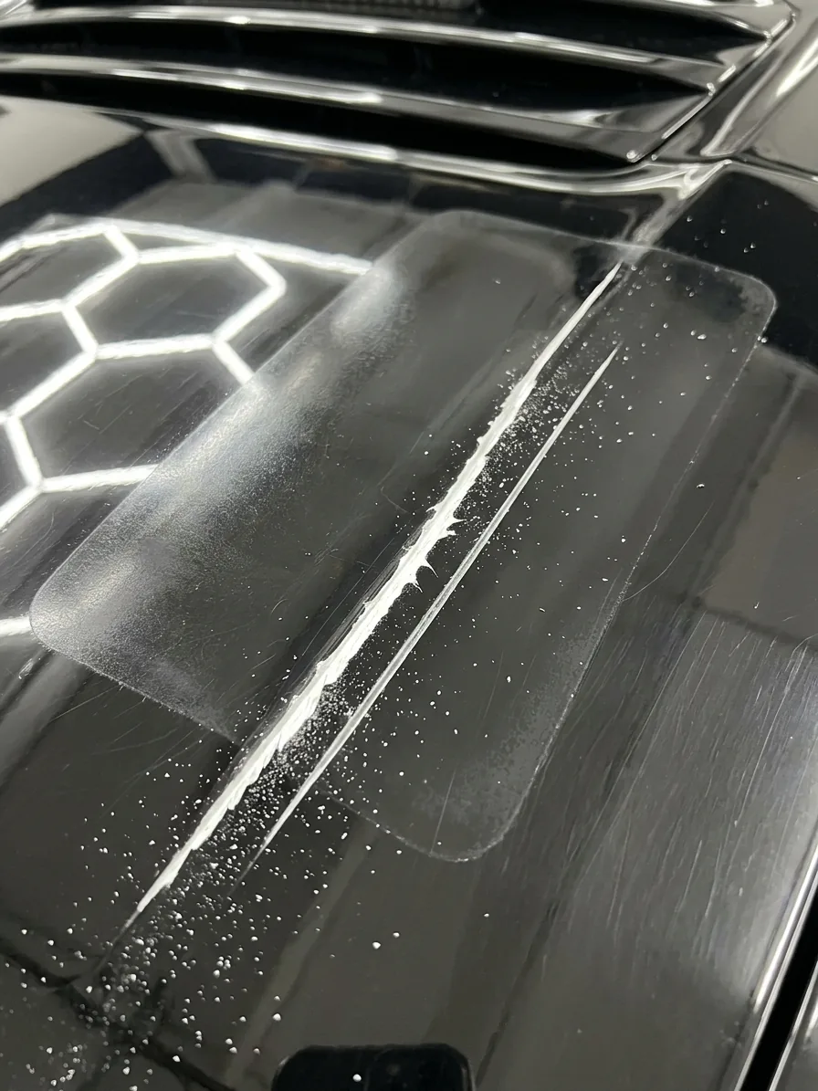 Black hood with a blade groove cut into the clear coat and the ghost outline of the old film