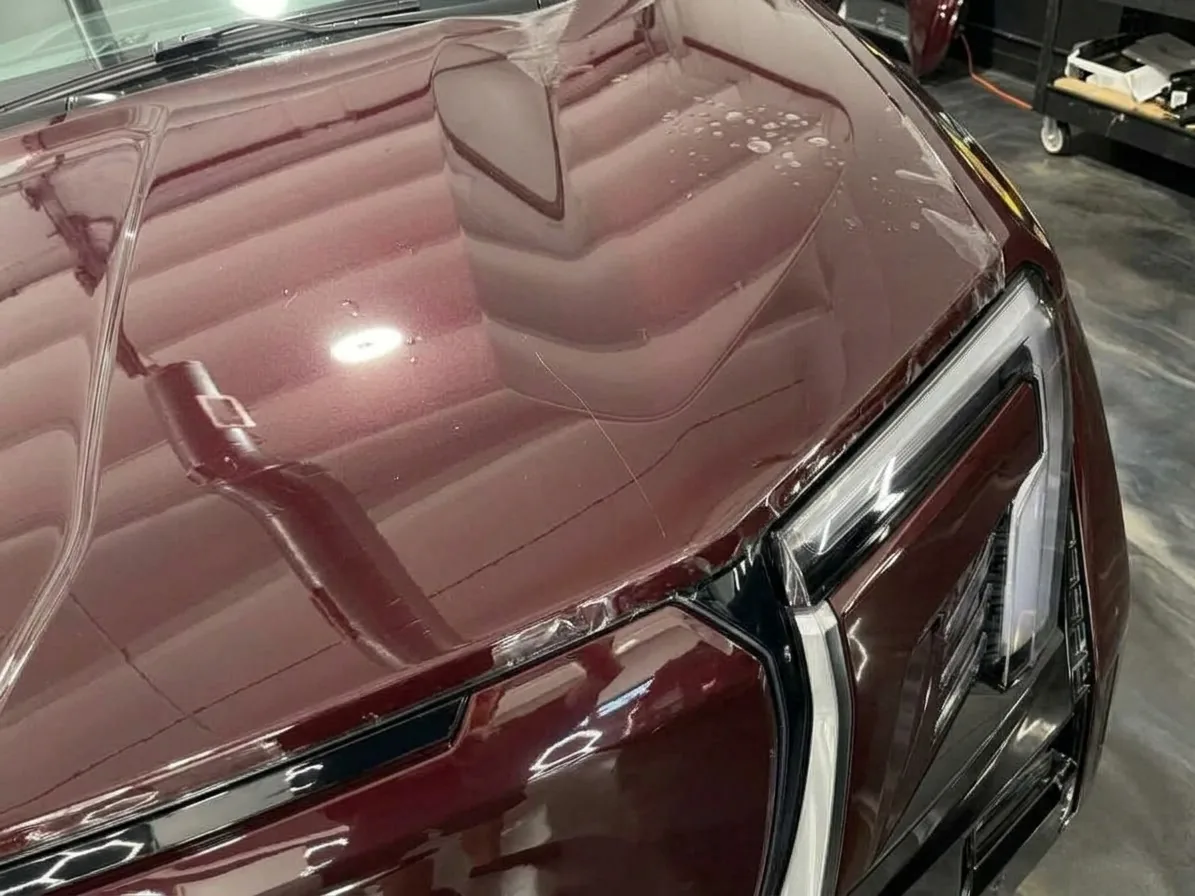 Dark red hood with dust and air bubbles trapped under the film