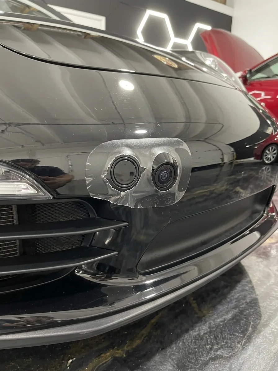 Black bumper with the film cut short and rough around the parking sensor and the camera