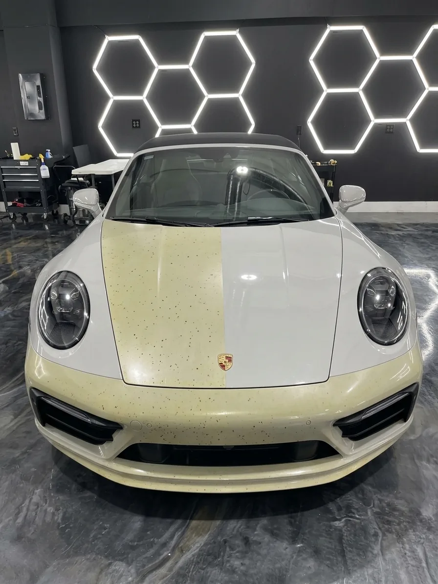White Porsche 911 with the old film on half of the hood and the bumper yellowed and stained against the white paint