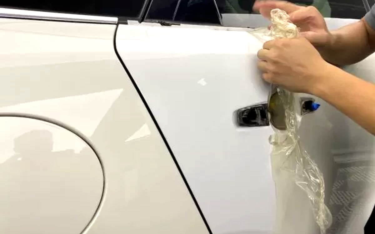 Old yellowed paint protection film being removed from a car door