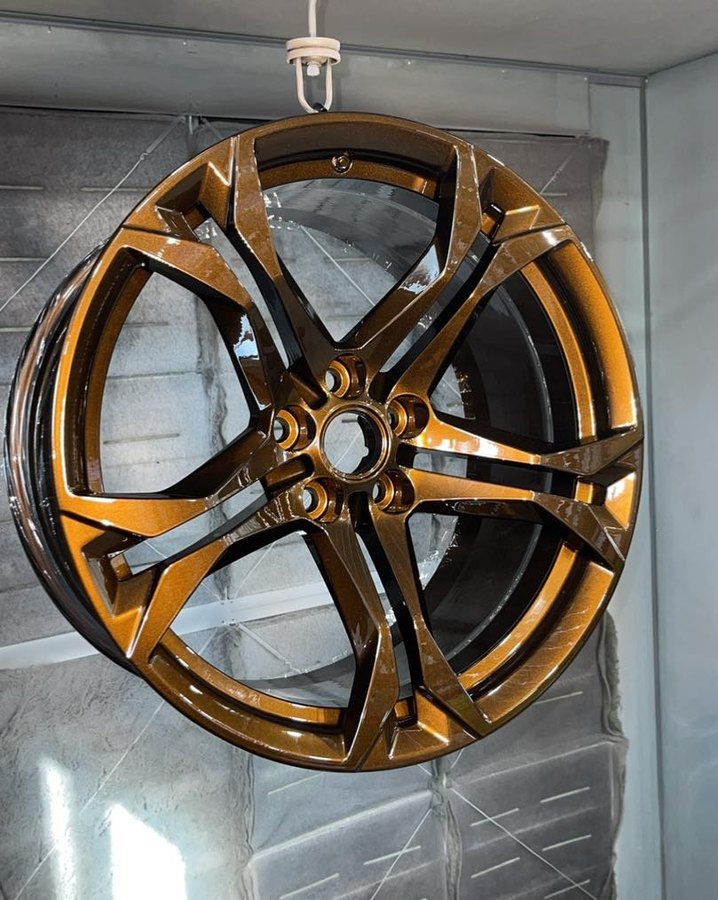 Wheel hanging in the powder coating booth with a fresh bronze finish